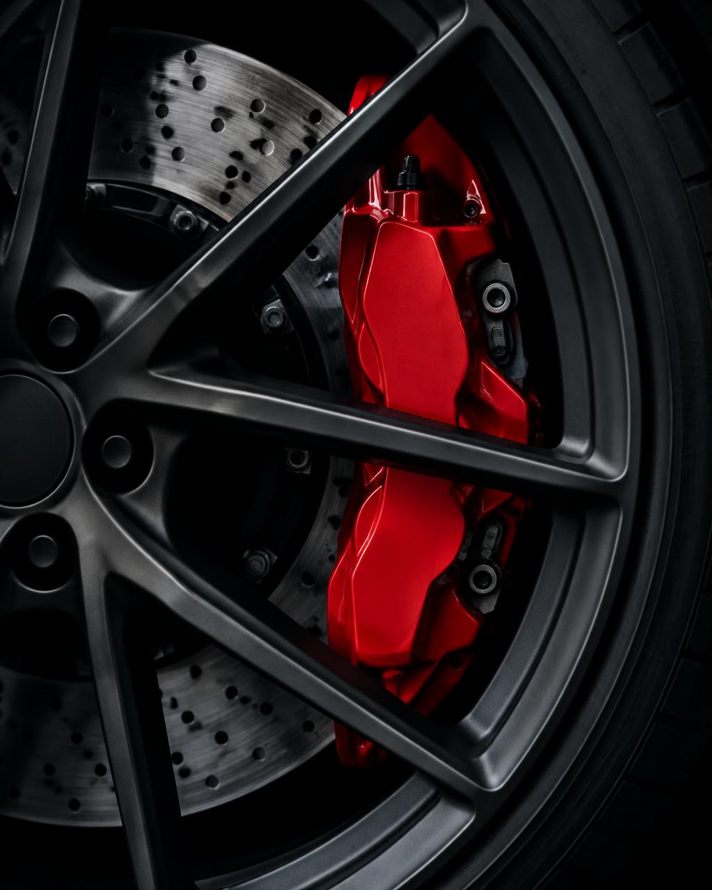 Red performance brake caliper behind a dark alloy wheel
